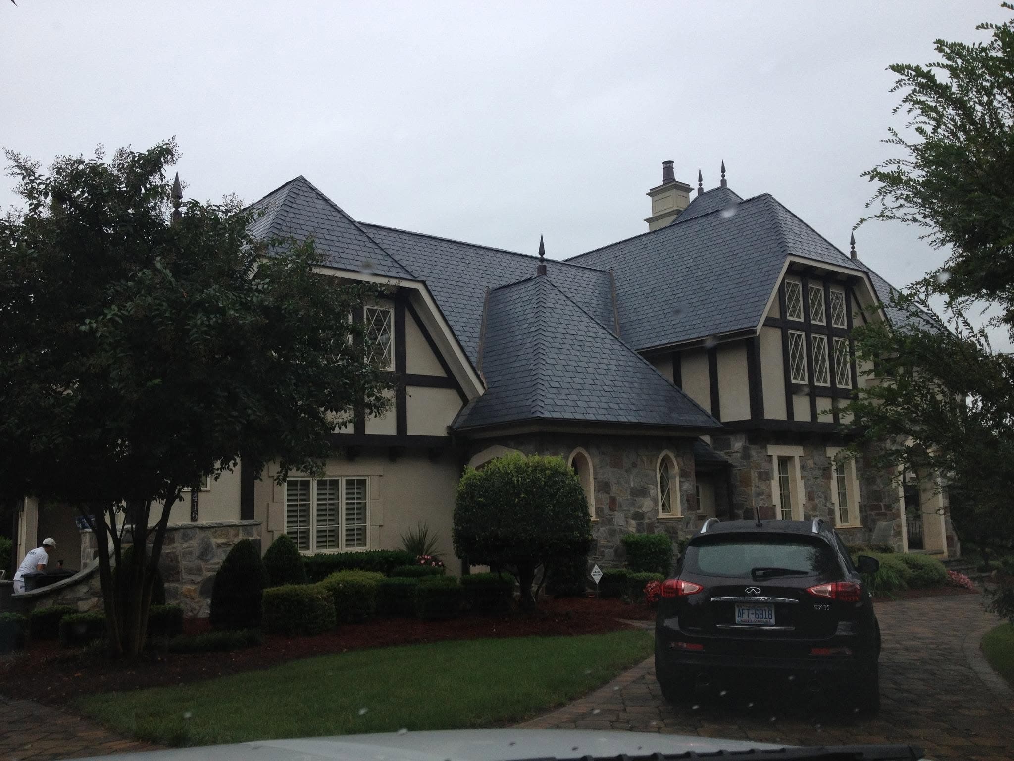 Tudor-style house in stone and painted stucco, with dark timber detailing and a steep pitched roof.
