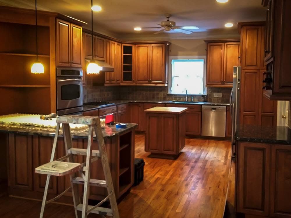 Kitchen before painting, with orange-toned honey oak cabinets, granite worktops and a central island.