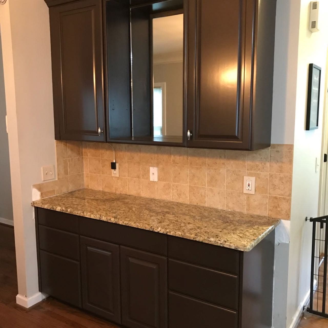 The same kitchen run after painting, with the cabinets finished in deep espresso above the original granite worktop.