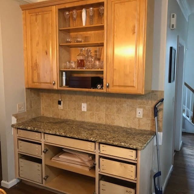 Kitchen run before painting, with pale maple upper and lower cabinets above a granite worktop.