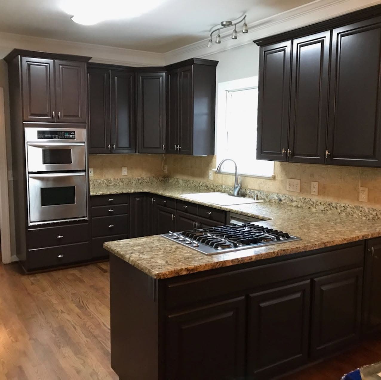 Finished kitchen with espresso-painted cabinetry, granite worktops and a stainless double wall oven.